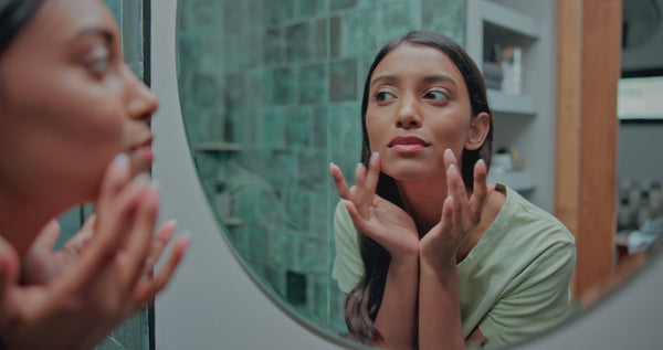 Woman touching her glowing skin after applying Vitamin C serum with Vitamin E – The North DNA clean skincare, antioxidant protection, hydration and brightening anti-dark spot care