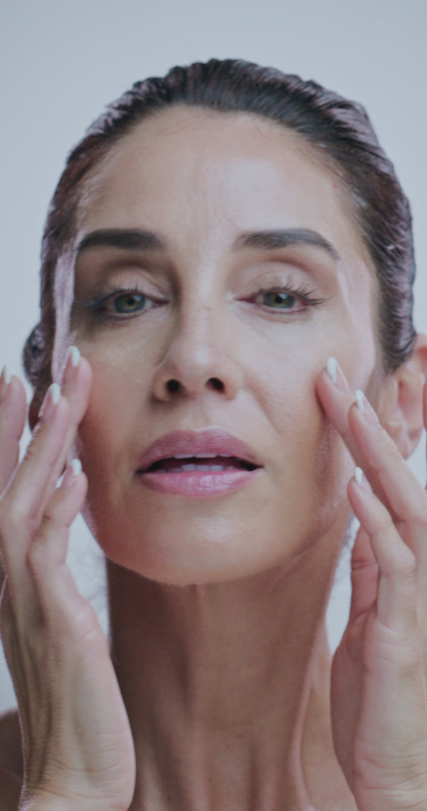 Mature woman touching her skin after applying peptide and hyaluronic acid anti-aging serum – The North DNA clean skincare for firmer, smoother, youthful-looking skin